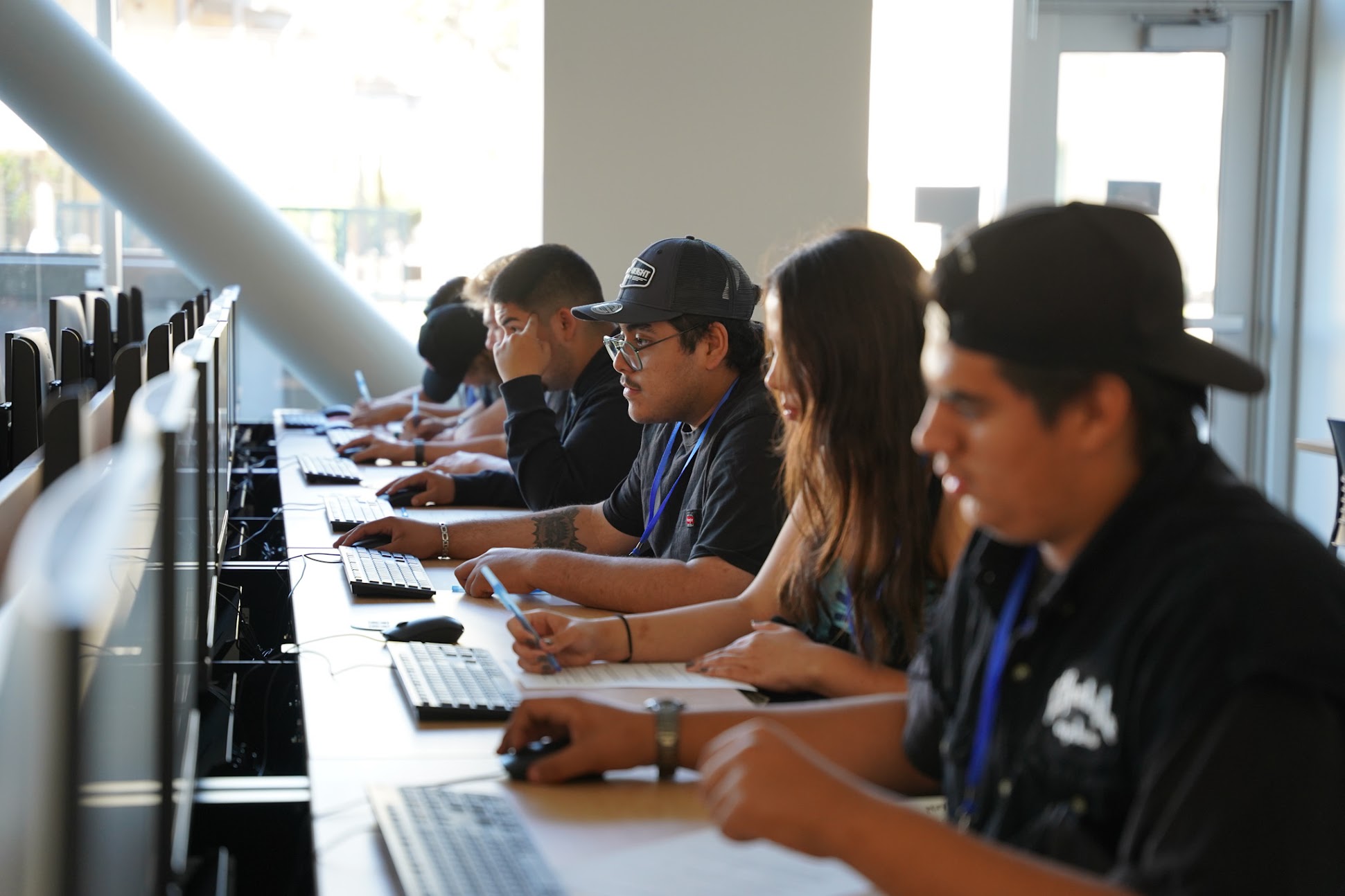 A row of students concentrating on desktop computers during a classroom computer-based exercise.