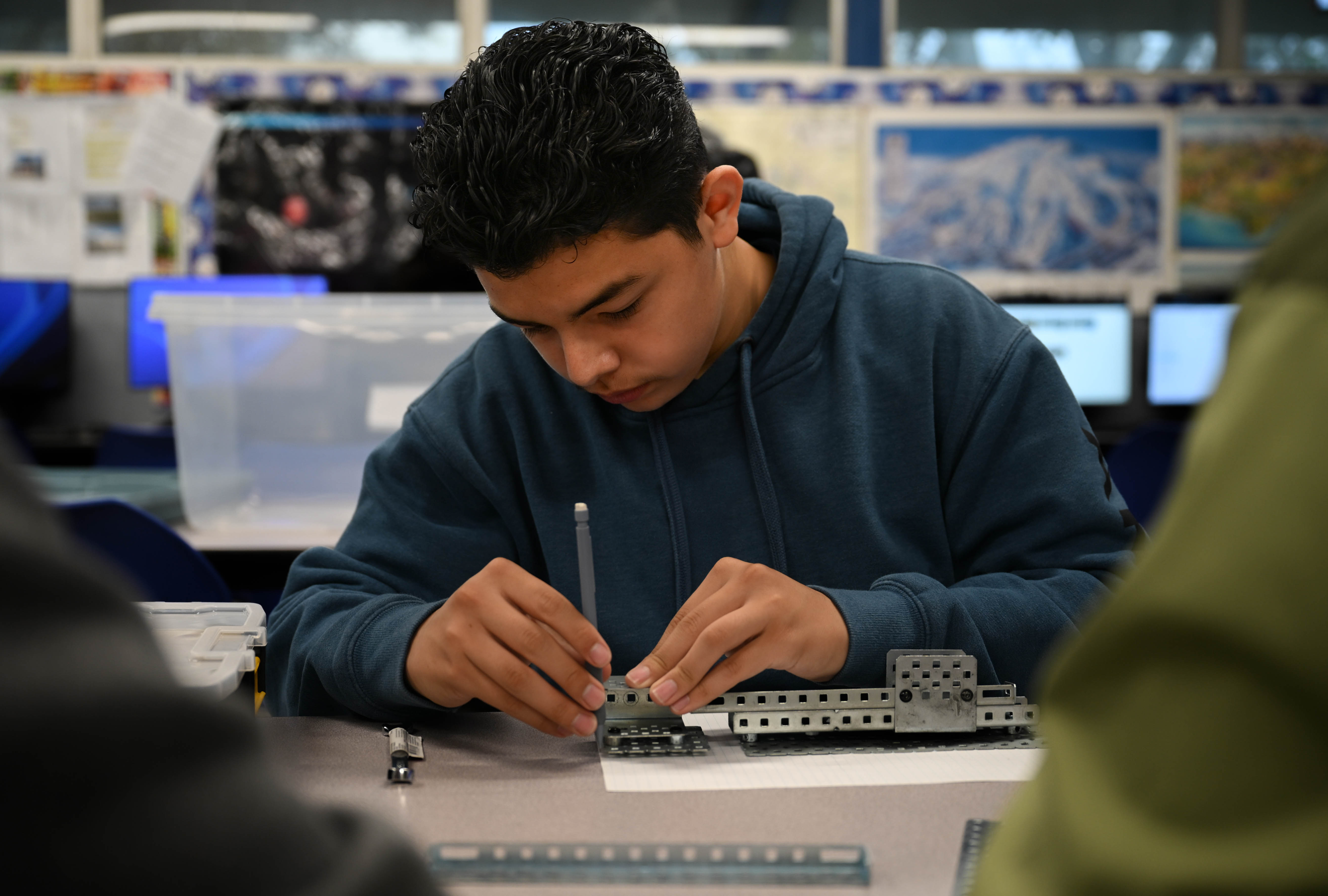 Student wearing blue hoodie and working with tools on an engineering project.