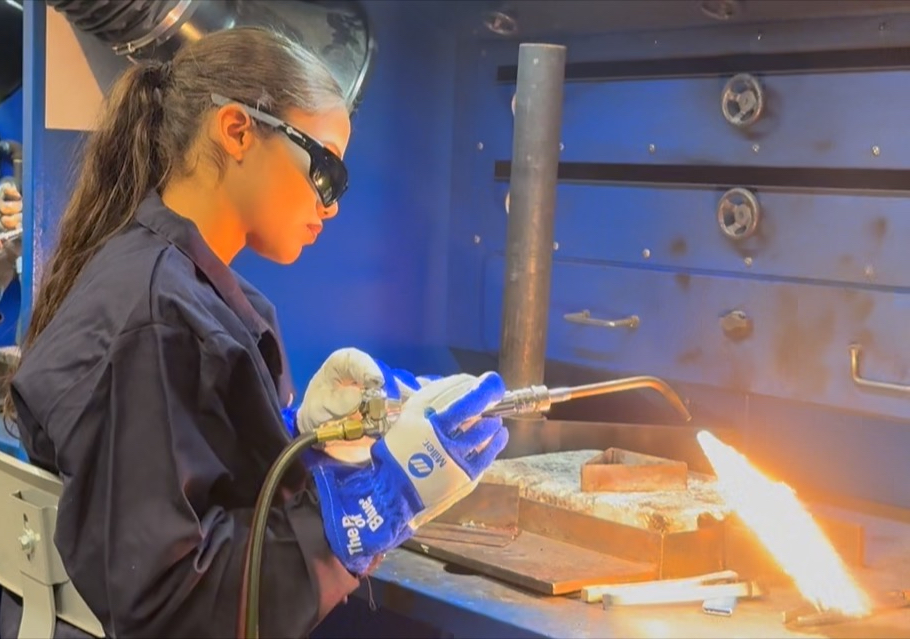 Girl practicing welding wearing safety goggles and protective suit